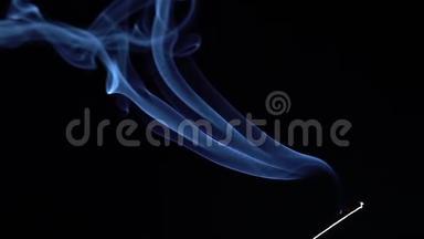 香棒在黑色的背景上燃烧和冒烟，从香中冒烟。 慢动作